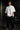 Person wearing a white t-shirt with a logo in a dark setting with a car in the background