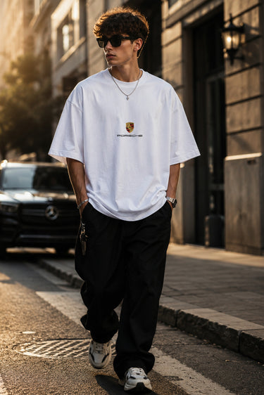 Person wearing a white t-shirt and black pants on a city street.
