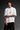 Person wearing a white t-shirt with a logo on a dark background
