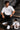 Man wearing a white RAM YODHA oversized t-shirt with 'Ram' graphic on front and Ram Yoddha artwork on back, seated on wooden steps.