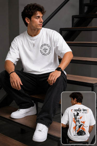 Man wearing a white RAM YODHA oversized t-shirt with 'Ram' graphic on front and Ram Yoddha artwork on back, seated on wooden steps.