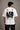 Man wearing a white oversized Royal Enfield t-shirt with a classic cannon graphic. Features a relaxed fit and modern streetwear aesthetic.
