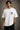 Man wearing a white oversized Royal Enfield t-shirt with a classic cannon graphic. Features a relaxed fit and modern streetwear aesthetic.