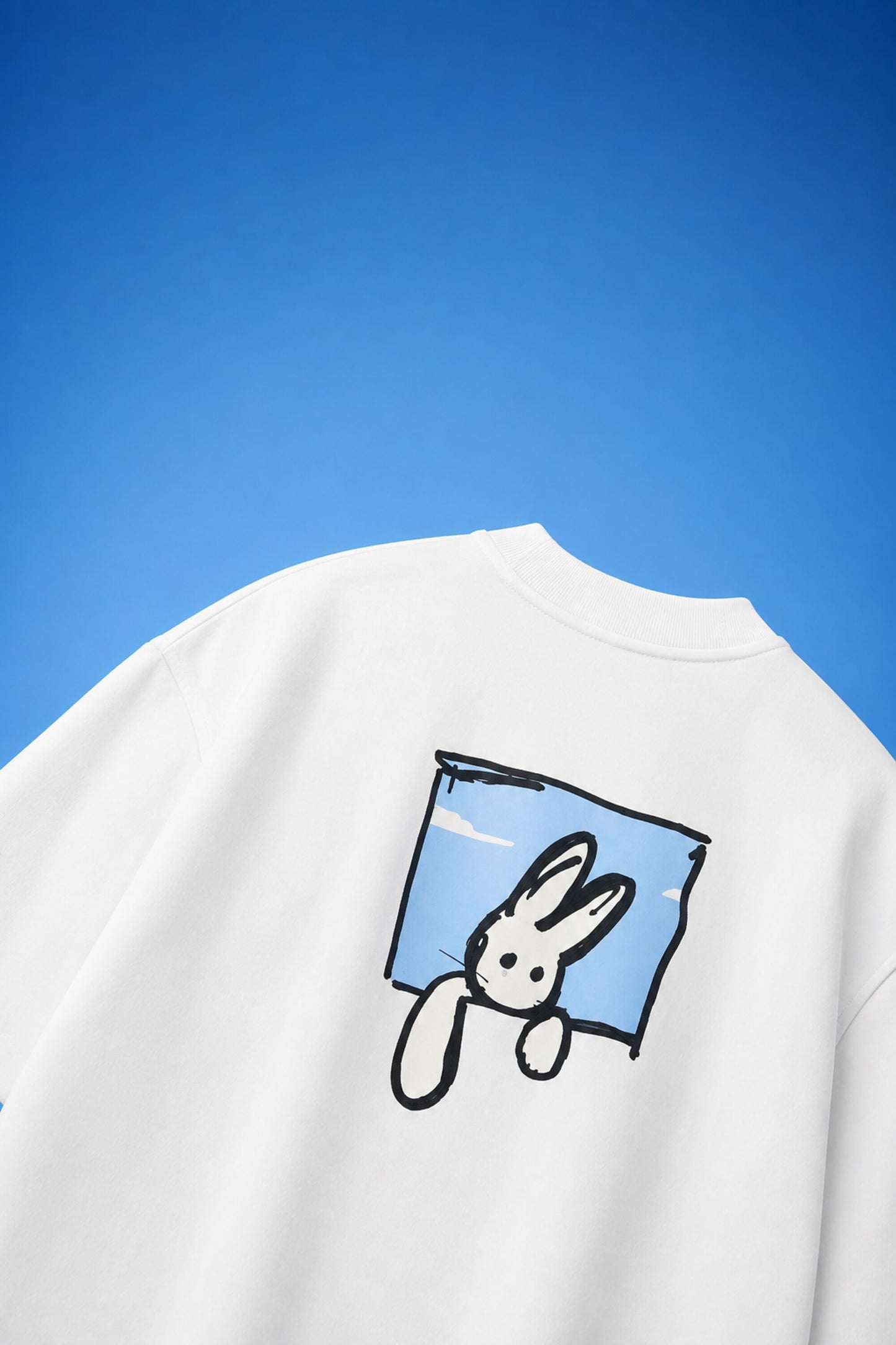 White oversized t-shirt with cute cartoon bunny peeking through sky blue window frame back print