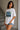 Woman wearing a white t-shirt with a Van Gogh painting design, standing in a neutral indoor setting.