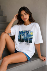 Woman wearing a white t-shirt with Van Gogh artwork sitting on stairs.