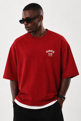 Man wearing a red Sumwon Club oversized t-shirt with white graphic print on front and back, styled for streetwear.
