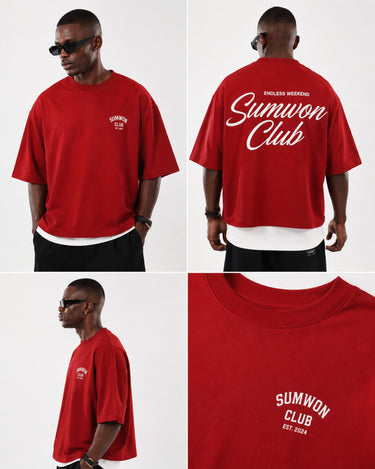 Man wearing a red Sumwon Club oversized t-shirt with white graphic print on front and back, styled for streetwear.