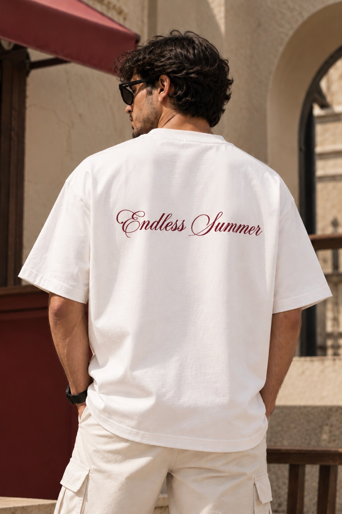 White oversized tshirt with THECOUTURECLUB dark maroon text and Endless Summer cursive print on chest, drop shoulder boxy fit, men India