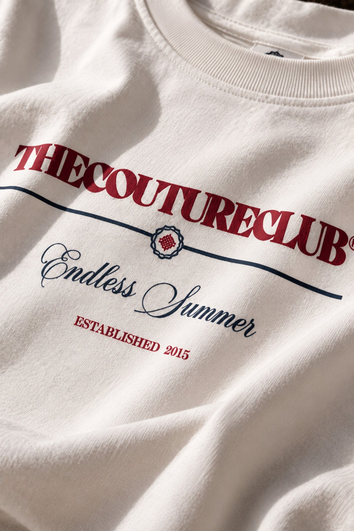 White oversized tshirt with THECOUTURECLUB dark maroon text and Endless Summer cursive print on chest, drop shoulder boxy fit, men India
