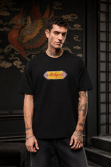 Black oversized t-shirt with Tibetan script in red on golden decorative banner, spiritual streetwear India - black