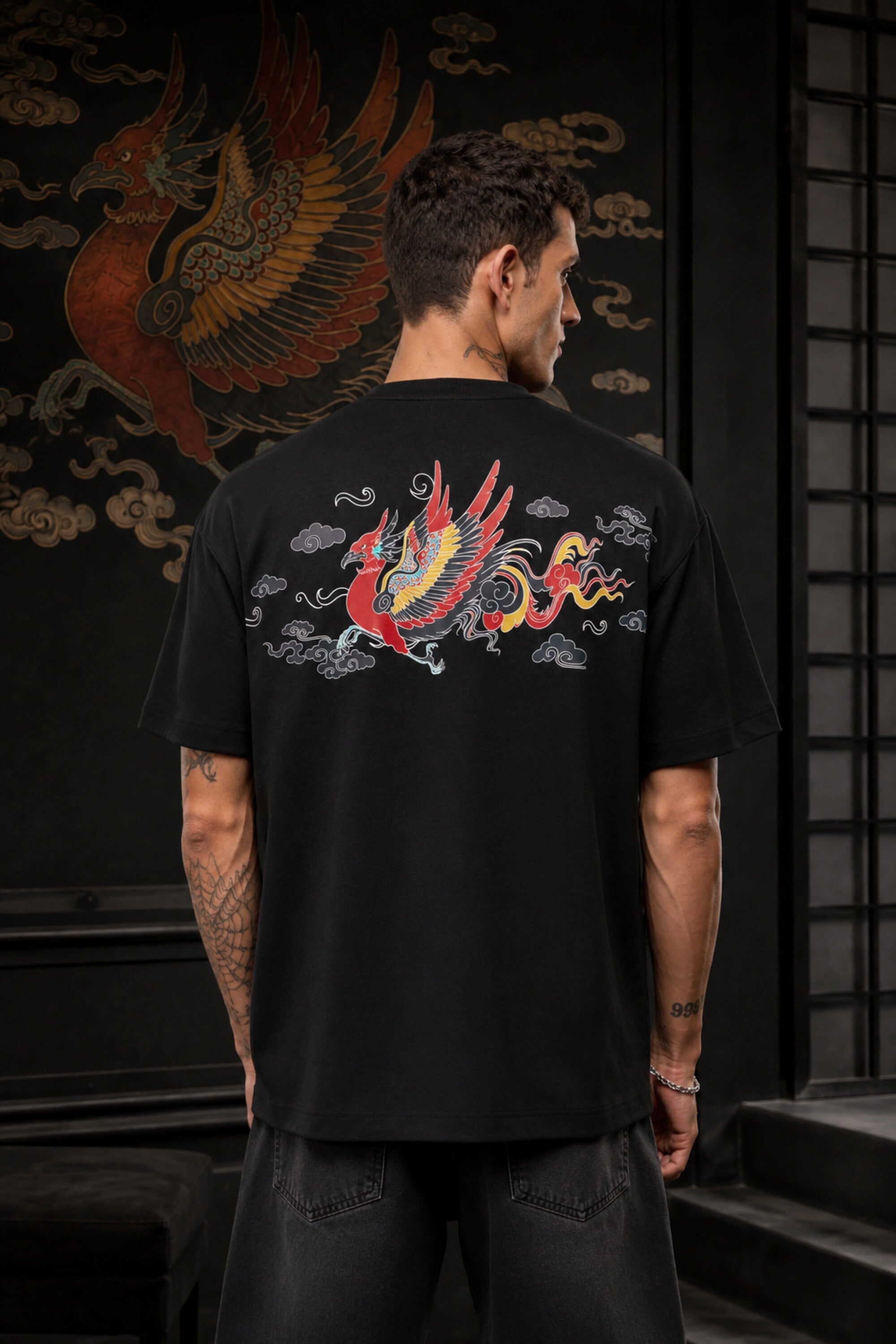 Black oversized t-shirt with Tibetan script in red on golden decorative banner, spiritual streetwear India