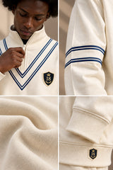 A cream-colored quarter-zip sweatshirt with navy blue stripes on the shoulders and a gold and navy crest patch on the chest. The image is a four-panel collage showing a model wearing the garment, close-ups of the sleeve stripes, the textured fabric, and a detailed view of the crest patch.
