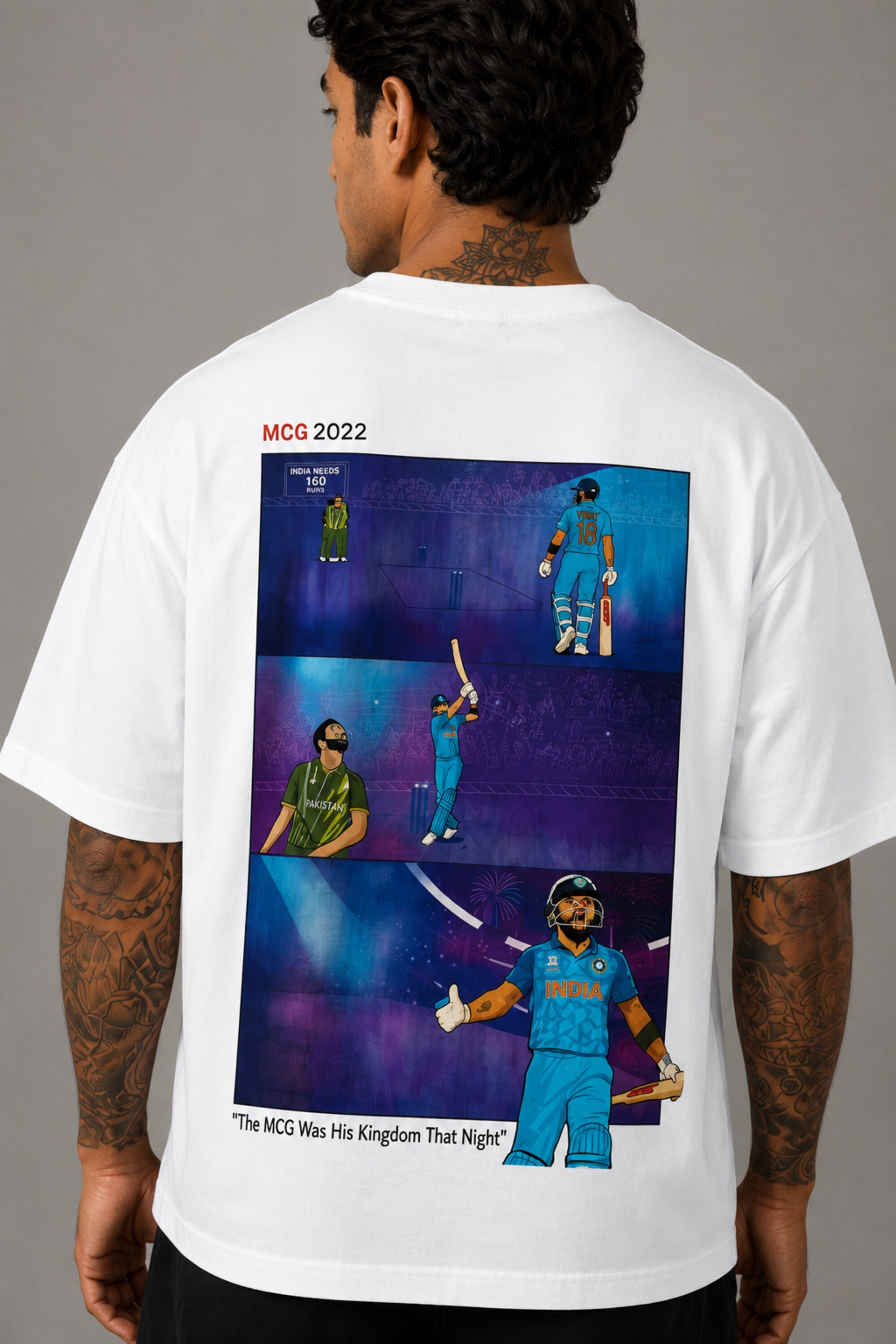 Man wearing a white VIRAT MCG 18 Vs PAK oversized t-shirt with a blue galaxy-themed '18' graphic. He is sitting on steps, showcasing the relaxed fit and streetwear style.