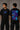 Man wearing a white VIRAT MCG 18 Vs PAK oversized t-shirt with a blue galaxy-themed '18' graphic. He is sitting on steps, showcasing the relaxed fit and streetwear style. - black