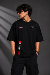Black oversized Audi RS t-shirt with iconic white and red RS logo on the chest and Audi rings graphic. Premium fabric detail shown.
