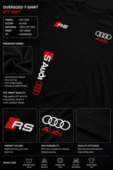 Black oversized Audi RS t-shirt with iconic white and red RS logo on the chest and Audi rings graphic. Premium fabric detail shown.