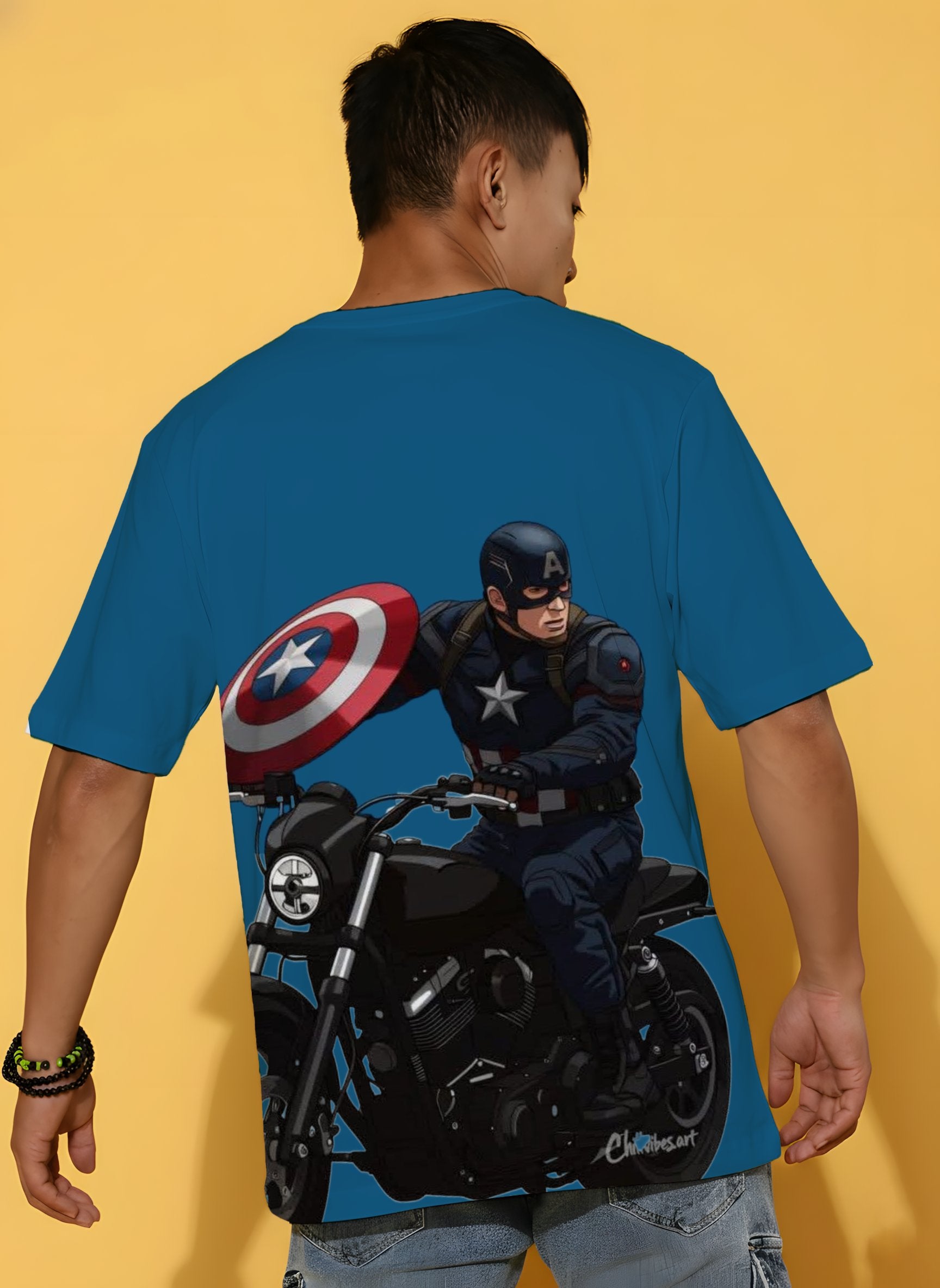 Person wearing a blue t-shirt with a superhero character on a motorcycle and shield.