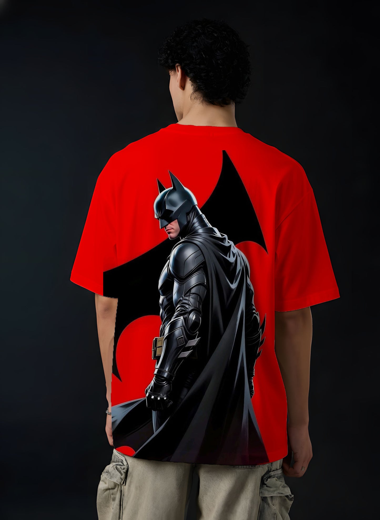 Person wearing a red t-shirt with a Batman graphic on the back against a black background