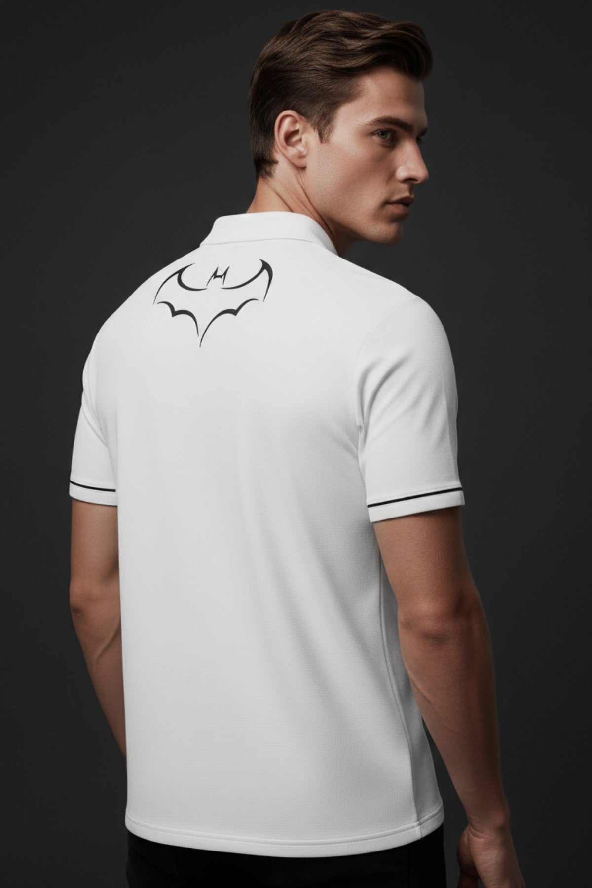 Man wearing a white polo shirt with a black bat logo on the back against a dark background