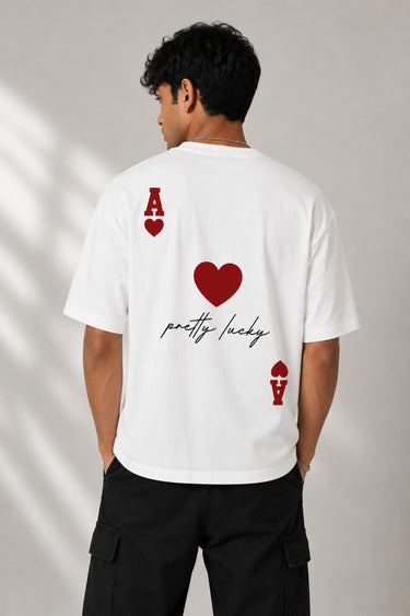 Man wearing a white oversized t-shirt with a large red Ace of Hearts graphic and 'pretty lucky' text on the back. Streetwear fashion.