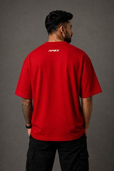 Close-up of a red Ferrari oversized t-shirt featuring the iconic yellow prancing horse logo and 'Ferrari 93' graphic. The fabric has a premium, textured look, showcasing high-quality print and material.