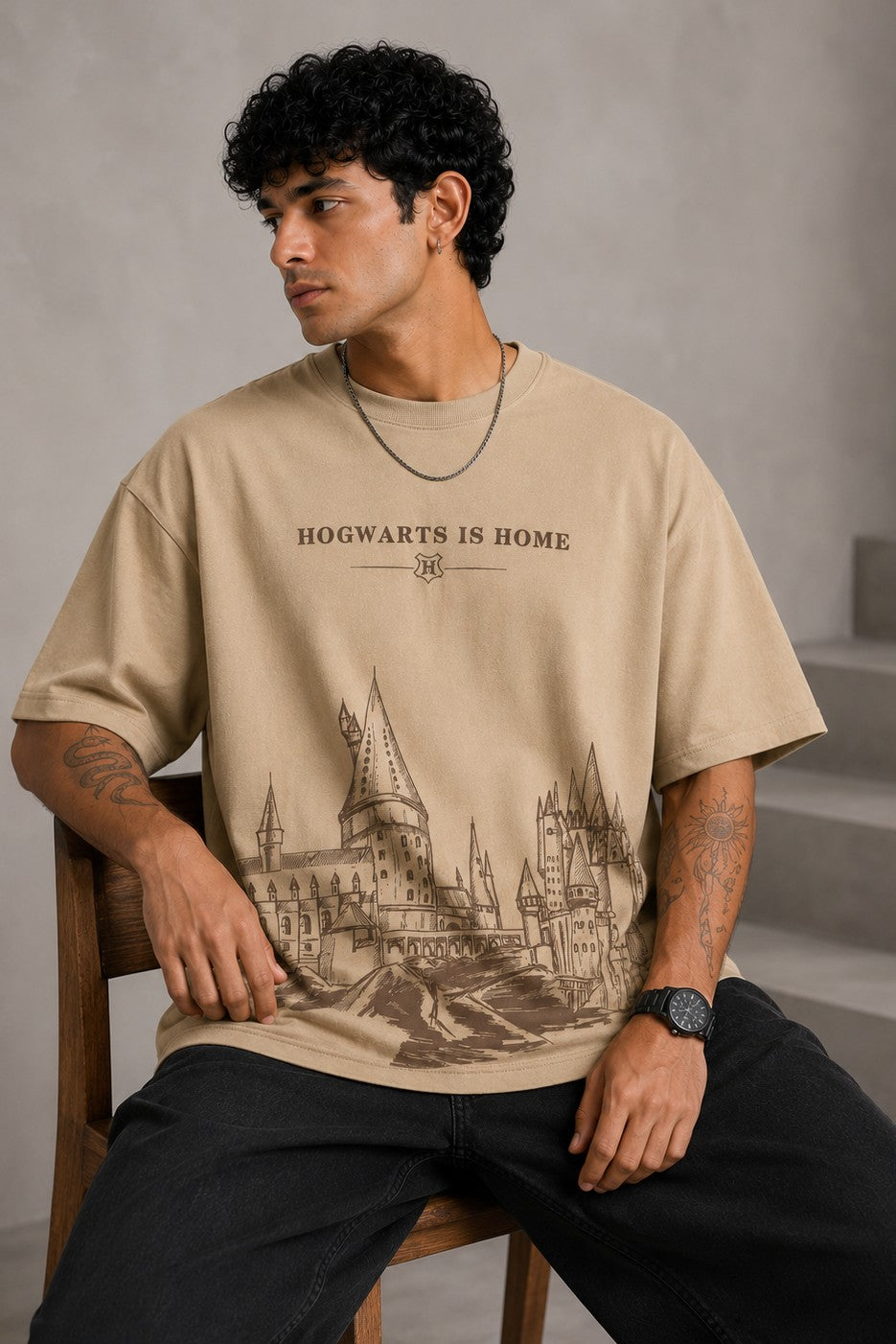 Beige oversized t-shirt with "Hogwarts is Home" text and a detailed sketch of Hogwarts castle. Premium cotton fabric visible.