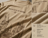 Beige oversized t-shirt with "Hogwarts is Home" text and a detailed sketch of Hogwarts castle. Premium cotton fabric visible.