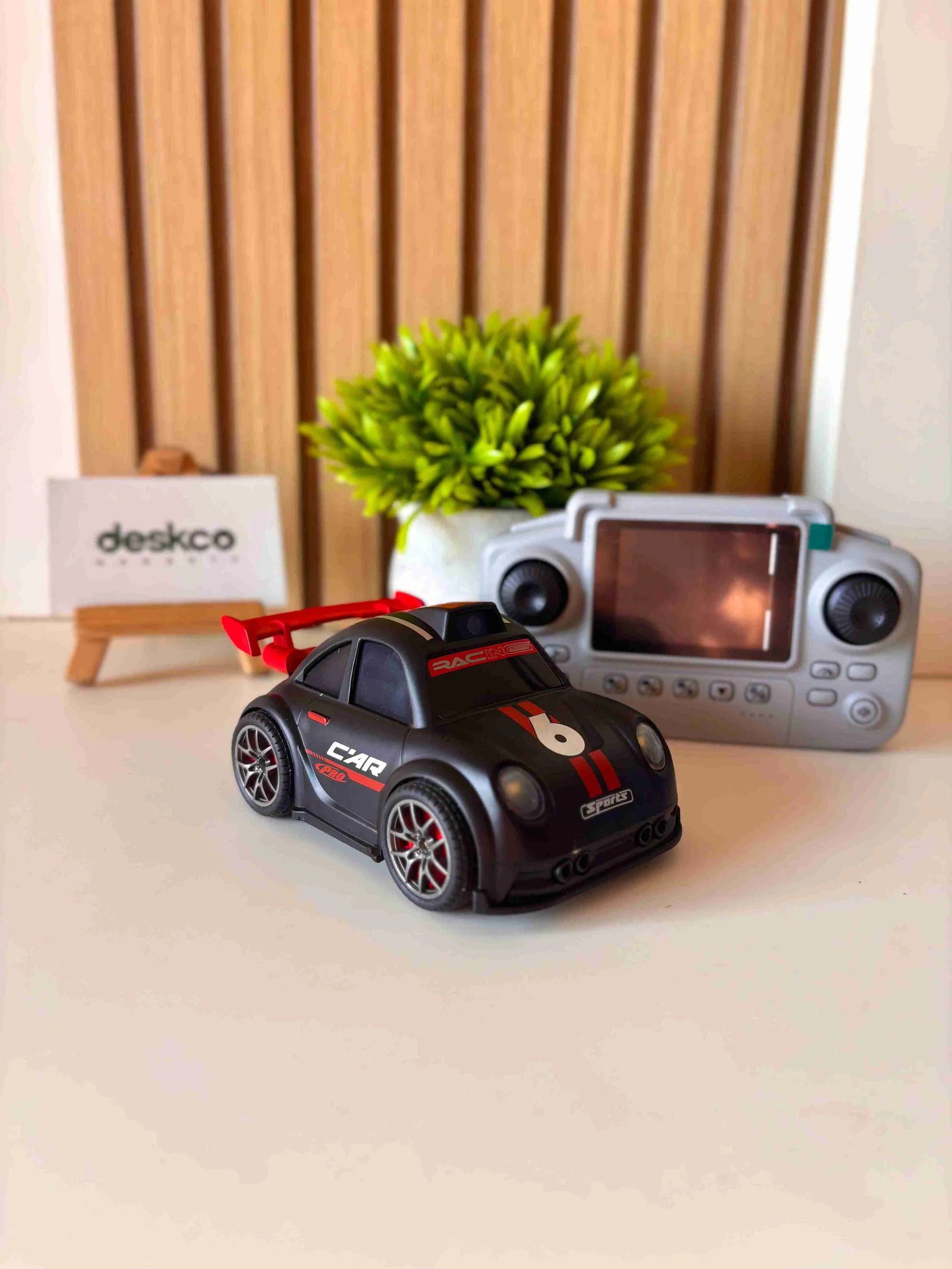Toy car with remote control on a desk, featuring the brand 'deskco'.