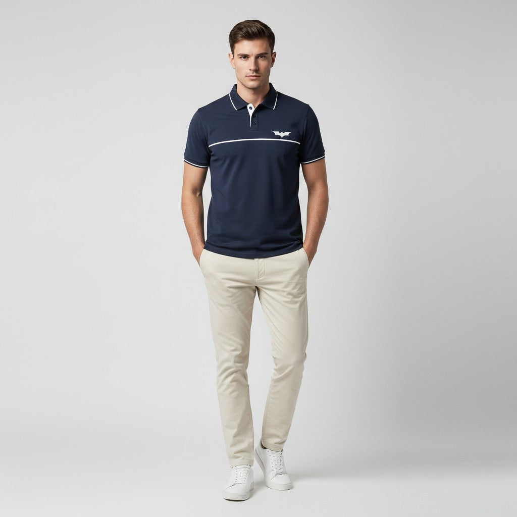 Man wearing a navy polo shirt with a logo and beige pants on a light gray background