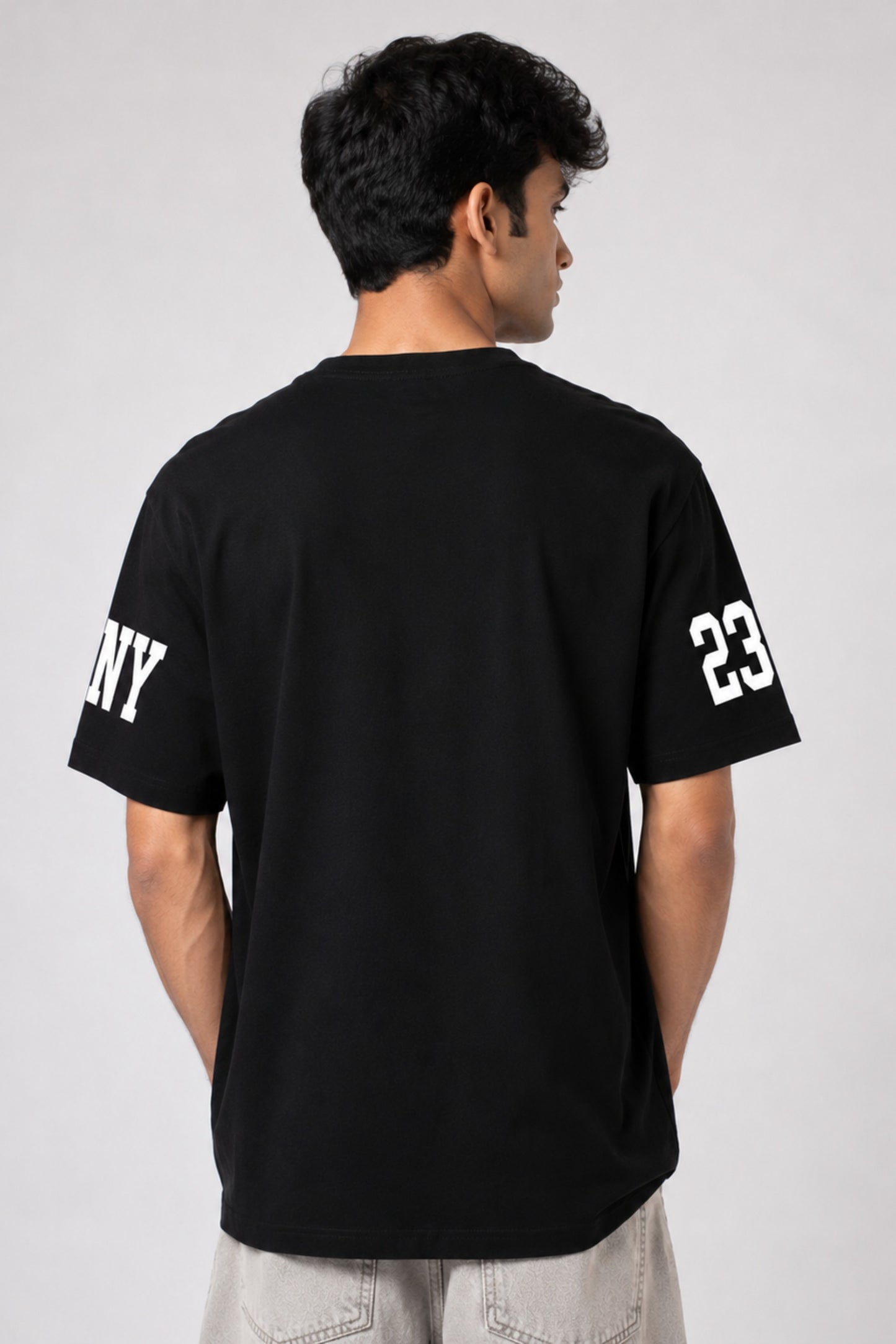 Person wearing a black t-shirt with 'NY' and number '23' on a plain background