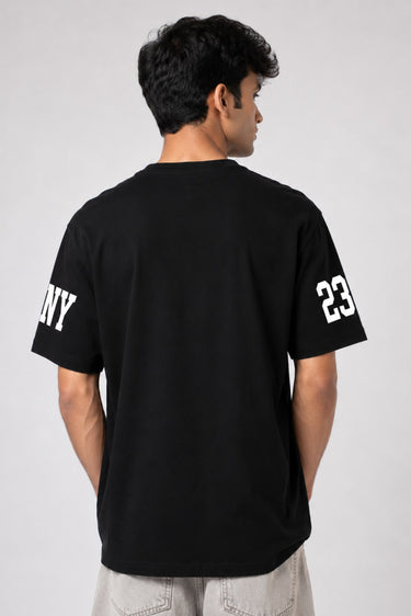 Person wearing a black t-shirt with 'NY' and number '23' on a plain background