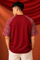 Dark red POPCASE 'Unstoppable' oversized t-shirt with white raised print, featuring ethnic patterned sleeves. Close-up shot showcasing fabric texture and print detail.