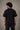 Back view of a man wearing an ENFIELD DESIGN black oversized t-shirt against a textured grey background. Features relaxed fit and premium cotton. - 2