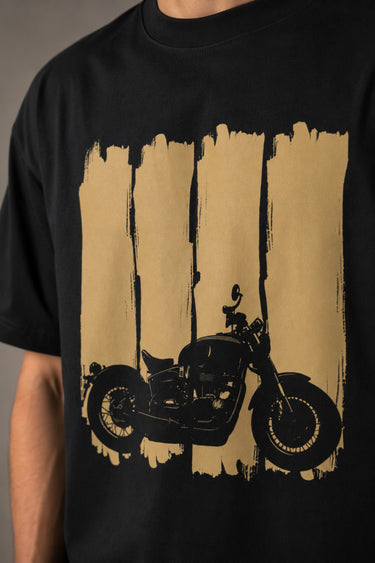 Back view of a man wearing an ENFIELD DESIGN black oversized t-shirt against a textured grey background. Features relaxed fit and premium cotton. - 4