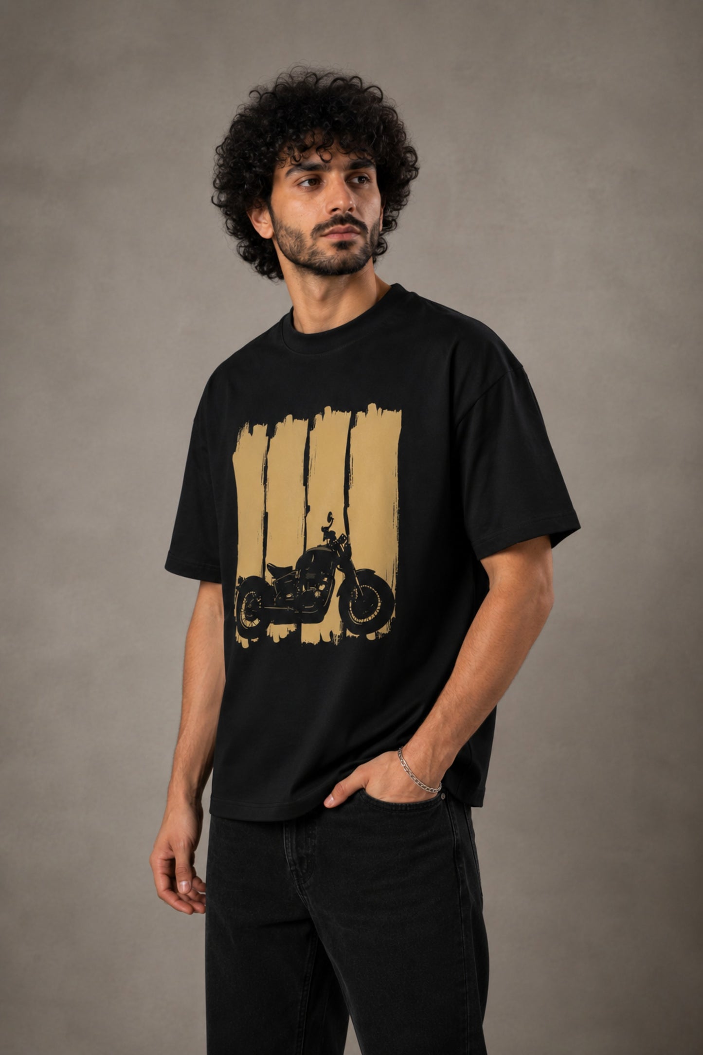 Back view of a man wearing an ENFIELD DESIGN black oversized t-shirt against a textured grey background. Features relaxed fit and premium cotton. - 7
