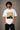 Back view of a man wearing an ENFIELD DESIGN black oversized t-shirt against a textured grey background. Features relaxed fit and premium cotton. - white