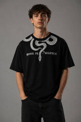 Beige oversized t-shirt with a detailed vintage-style grey snake graphic and 'MOVE IN SILENCE' text. The fabric is soft-washed premium cotton.