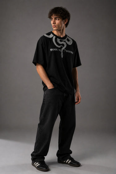 Beige oversized t-shirt with a detailed vintage-style grey snake graphic and 'MOVE IN SILENCE' text. The fabric is soft-washed premium cotton.