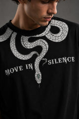 Beige oversized t-shirt with a detailed vintage-style grey snake graphic and 'MOVE IN SILENCE' text. The fabric is soft-washed premium cotton.