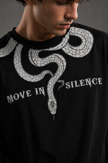 Beige oversized t-shirt with a detailed vintage-style grey snake graphic and 'MOVE IN SILENCE' text. The fabric is soft-washed premium cotton.