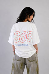 White oversized t-shirt from The Six Design featuring a bold red and blue graphic print of the numbers 3, 6, and 9. The t-shirt has a relaxed fit and is made of premium cotton.