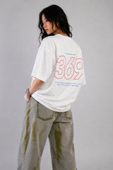 White oversized t-shirt from The Six Design featuring a bold red and blue graphic print of the numbers 3, 6, and 9. The t-shirt has a relaxed fit and is made of premium cotton.