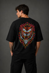 Man wearing a black UNSTOPPABLE DESIGN oversized t-shirt with a vibrant, detailed graphic of a roaring tiger surrounded by red flowers and a geometric frame on the back.